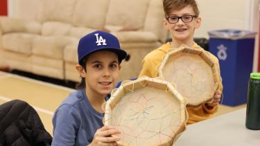Two grade 5 students holding up the drums they made