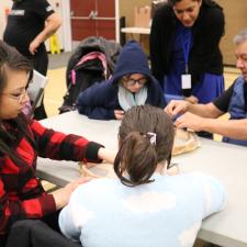 Knowledge Keeper Darren Charlie and Two female parents support their grade 5 students with their hand drum