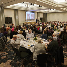 Large group of people sitting at round dinner tables