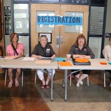 Four women sitting at the registration table waiting to greet families