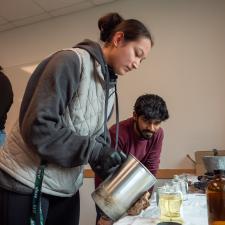 Female student pouring a candle as a male student watches